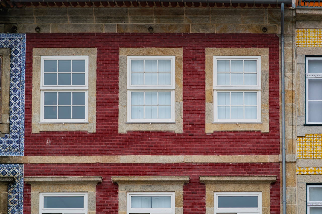 Vibrant red brick facade with traditional Portuguese white windows in Porto, Portugal.